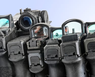 Tactical military gear including an assault rifle, pistol, helmets, and ammo crates on camouflage netting.