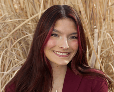 Headshot of Quesada Stoner in a maroon suit.