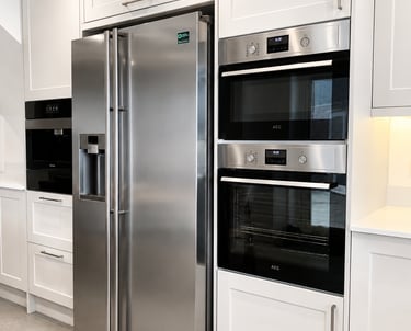 Stainless steel American-style fridge freezer alongside integrated double ovens in Iffley