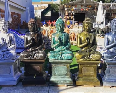 A row of colorful ceramic Buddha statues for sale at an outdoor garden decor market.
