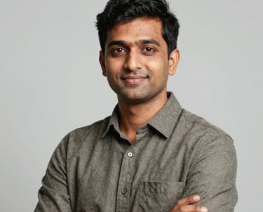 A professional portrait of a tech expert in business casual attire in a South Asian / Global setting, looking confident and approachable, set against a clean, light grey studio background.