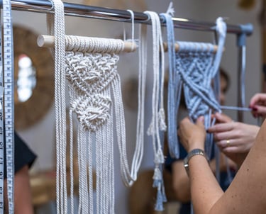 Proyectos de tapices de macramé hechos a mano colgados en un soporte de un taller de arte textil