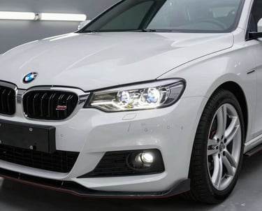 A professional car detailer applying ceramic coating on a sleek black car under natural daylight.