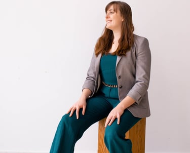 Rachel Krayenhoff in a teal jumpsuit and grey blazer posing for a business headshot.