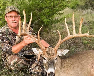 Hunter posing with a large 170 plus class trophy whitetail buck in the Mason County Texas Hill Country.