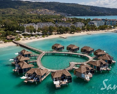 Aerial view of luxury over-the-water bungalows at a Sandals tropical Caribbean beach resort.