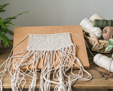 Tapete hecho de manera artesanal, sobre una mesa de madera con hilos de macramé