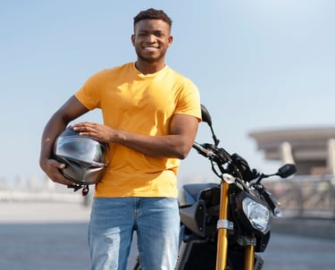 A Motorcyclist is holding a helmet and standing next to his bike on the training track.