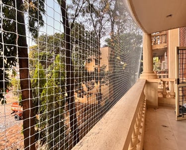 A clean, secure balcony fitted with sturdy pigeon netting under bright daylight.