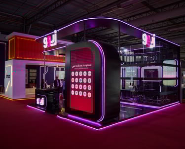 Modern neon-lit exhibition stand with purple LED accents and digital display at a trade show.