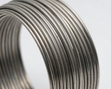 Detailed close-up of coiled stainless steel wire glinting with sharp reflections.