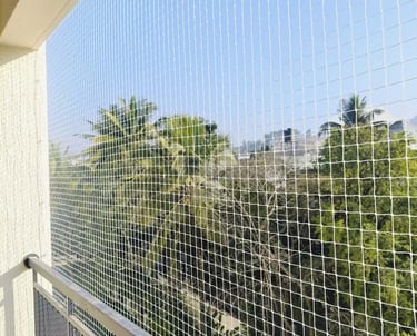Wide view of a high-rise apartment balcony secured with safety nets by Arjilli Enterprises.