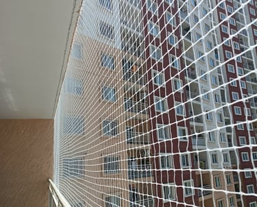 A skilled technician from Arjilli Enterprises installing a sturdy pigeon net on a balcony overlookin