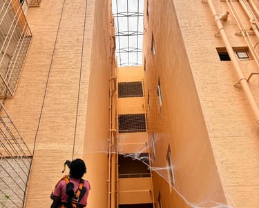 Technician carefully installing anti-pigeon netting on a Pallavaram apartment duct area.