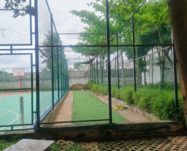 Close-up of tightly fastened basketball court nets with players warming up in the background.
