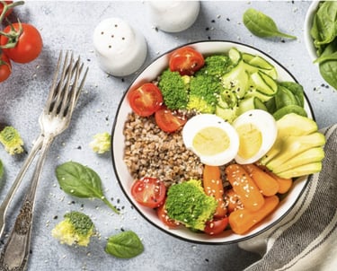 Colorful bowl with avocado, egg, broccoli, tomatoes, grains, and fresh greens for holistic nutrition
