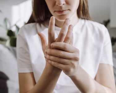 A woman holding her hand to relieve joint pain, arthritis, or carpal tunnel symptoms.
