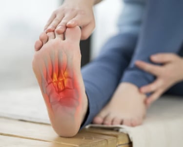 Anatomical overlay showing foot pain and inflammation in the metatarsal bones of a person holding their foot.
