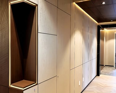 Modern hallway interior featuring cream wall panels, recessed LED lighting, and light oak herringbone flooring.