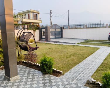 A modern garden landscape with a paved stone walkway, green lawn, and a stylish hanging egg chair.