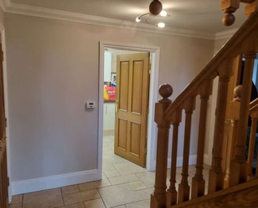 Finished hallway with newly painted walls, wooden staircase, and interior door.