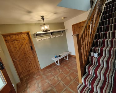 Rustic entrance hallway, with a white wall/ceiling, a pale-green wall, and red-slab flooring.