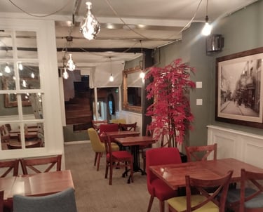 Cosy restaurant dining room, with wooden chairs/tables, and fresh grey and white walls/ceiling.