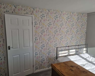 Bedroom wall with bright, botanical wallpaper.