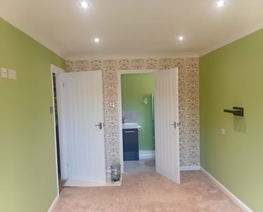 A feature wall with a repeating flower design, and the surrounding walls painted a pale green.