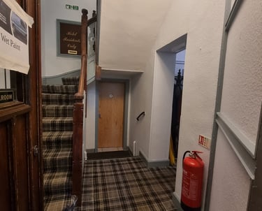 Stairway base with grey, stippled walls and tartan-like floor in a hotel.