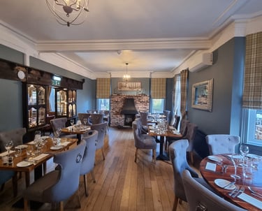 A well-decorated restaurant dining area with a white ceiling, grey walls, and wooden floor.