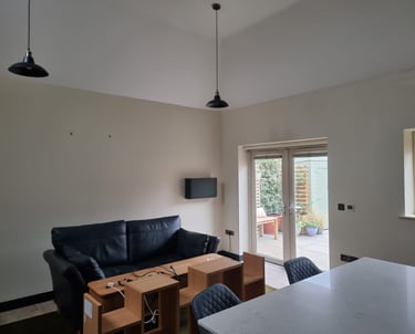 A minimalistic living room, with cream-painted walls and a high, white ceiling.