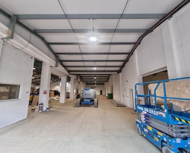 A long, in-use industrial unit, with painted white walls, supports, and ceiling.