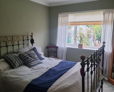 A furnished bedroom, with dark grey/green walls and white ceiling/coving.