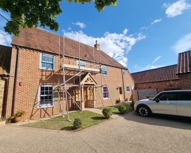 Scaffolding set up on the exterior of a large brick residential house.