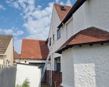 Exterior of the back of a white, stippled residential home, with maroon rooftiles.
