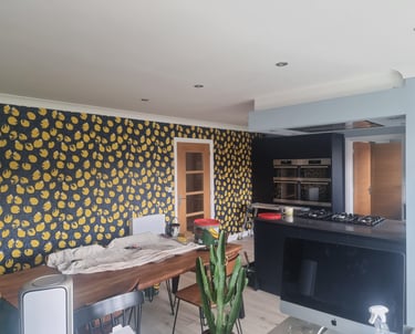 Kitchen in a residential home, with a large wall covered in dark-blue and lemon motif wallpaper.
