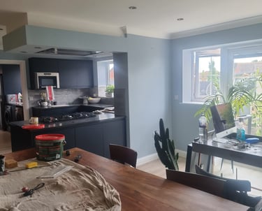 An open plan kitchen and dining room, with fresh, light-grey painted walls and white ceiling/coving.