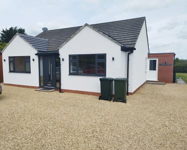 Exterior of a white bungalow with modern-style, black door and windows.