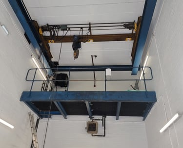 An industrial pure-white, freshly-painted room, with a high ceiling and lift-machinery.