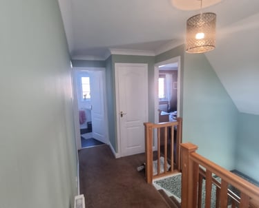 Freshly painted hallway and staircase walls in a mint colour, with 3 painted-white doors.