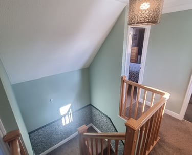 Residential house stairway, with light-green walls halved by static-like wallpaper.