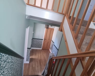 Interior of stairs/hallway from mid-landing, with half grey walls and half dark, floral wallpaper.