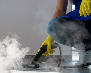 a person in a blue shirt and yellow gloves is using a steam cleaner