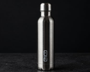 A minimalist, low-key lighting shot of a high-end metal water bottle with futuristic branding, standing on a dark, reflective surface.