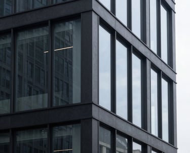 Minimalist photography of a sleek, dark-gray modern building exterior with large glass panels, in a North American business district.