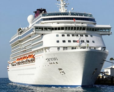 A vibrant cruise ship sailing past turquoise Caribbean waters under a sunny sky.
