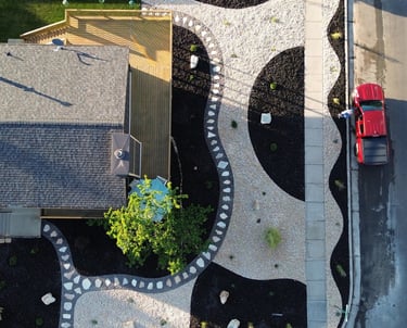 Aerial view of a modern xeriscape front yard featuring decorative black mulch and white gravel patterns.