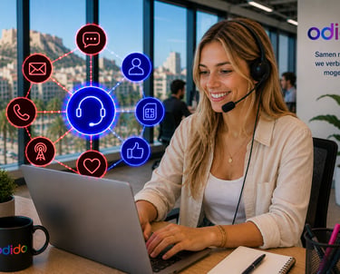 A smiling Odido customer service agent with a headset working on a laptop in a modern office.