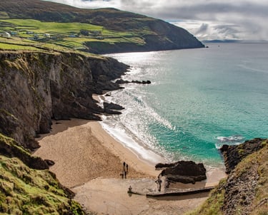 Turquoise ocean waves crashing on the sandy Dunmore Head beach along the rugged Dingle Peninsula coast in Ireland.